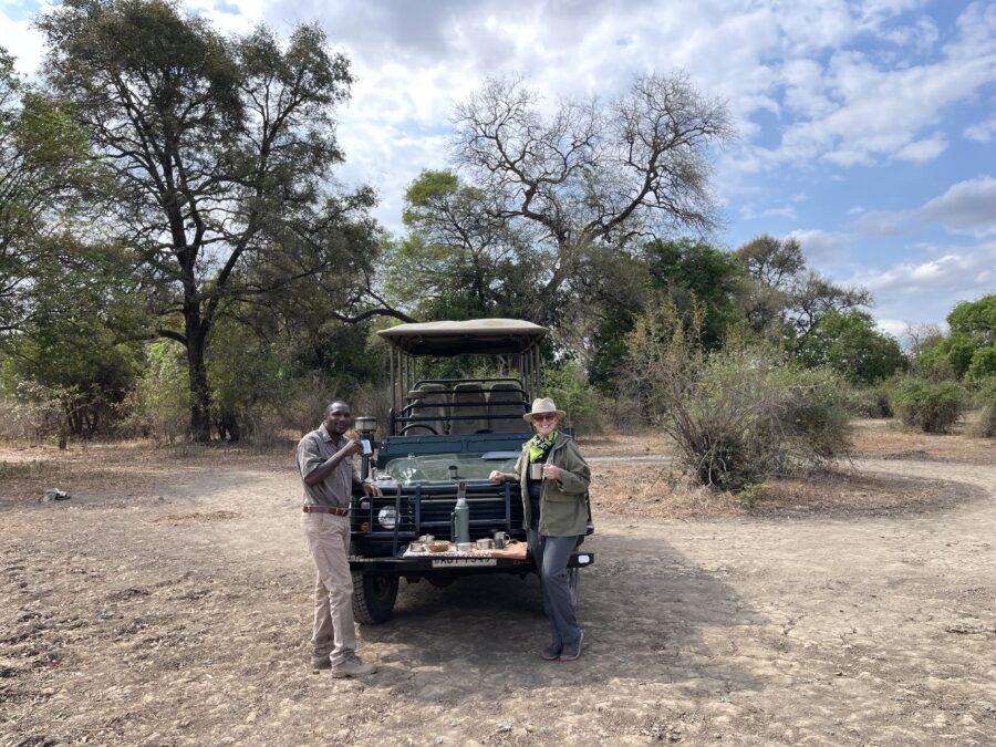 Kerry and her safari tour guide enjoying a cup of coffee in the African wilderness in front of their jeep.