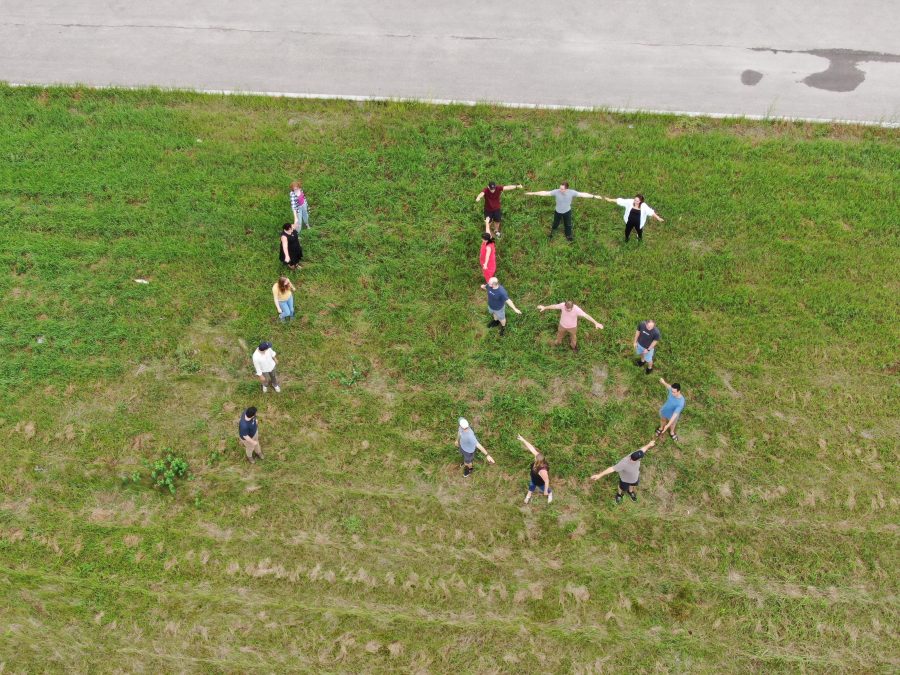 Rotessa staff on a grassy lawn creating a "15" with their bodies.